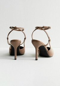 Sandalias de tacón alto marrones con correas en el tobillo, acabado de charol brillante y tacones finos de aguja. Hebilla ajustable para un ajuste seguro.