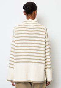 Gestrickter Pullover mit hohem Kragen, der abwechselnd breite beige und weiße Streifen aufweist, überschnittene Schultern und eine lockere Passform hat.