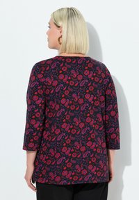 Langärmliges Oberteil in Schwarz mit floralem und Paisleymuster in Rot und Lila. Hergestellt aus weichem Stoff, verfügt es über einen runden Ausschnitt und eine lockere Passform.