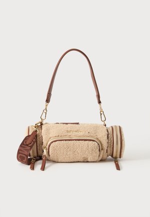 Petit sac à main cylindrique beige en sherpa avec des anses en cuir marron, poche avant zippée, fermetures éclair dorées et logo Steve Madden sur le devant.