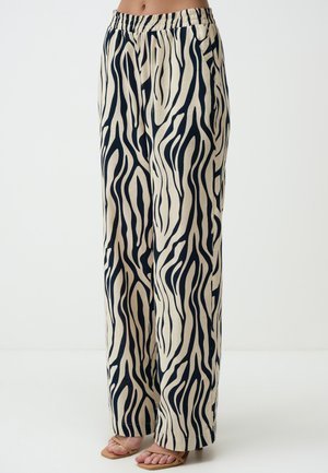 Pantalons larges en mélange de lin avec un fond beige et des rayures zèbre noires, taille élastique et poches latérales.