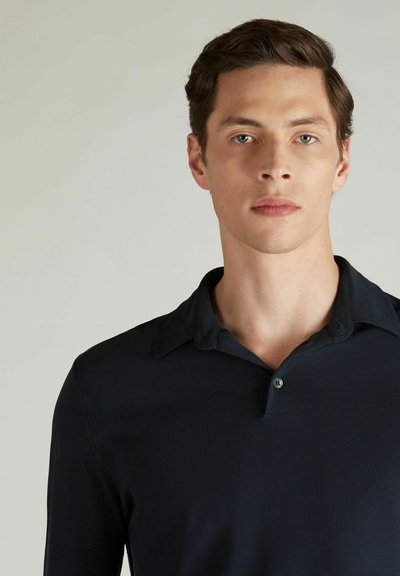 Polo shirt à manches longues bleu marine avec patte de boutonnage et une texture douce et lisse. Dispose d'un col classique et d'un design minimaliste.