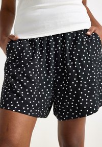 Sorte shorts med hvide prikker, med elastisk talje, løs pasform og sidelommer, lavet af letvægtsstof.