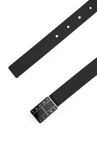 Μαύρη δερμάτινη ζώνη με ορθογώνιο μεταλλικό πόρπη που φέρει ανάγλυφη τη φράση "TOMMY JEANS" σε λευκό χρώμα. Ομαλή υφή και πέντε ρυθμιζόμενες τρύπες.