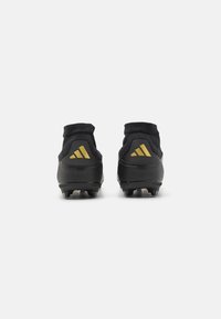 Black soccer cleats with a textured upper, sock-like collar, and gold accents on the heel featuring the Adidas logo.