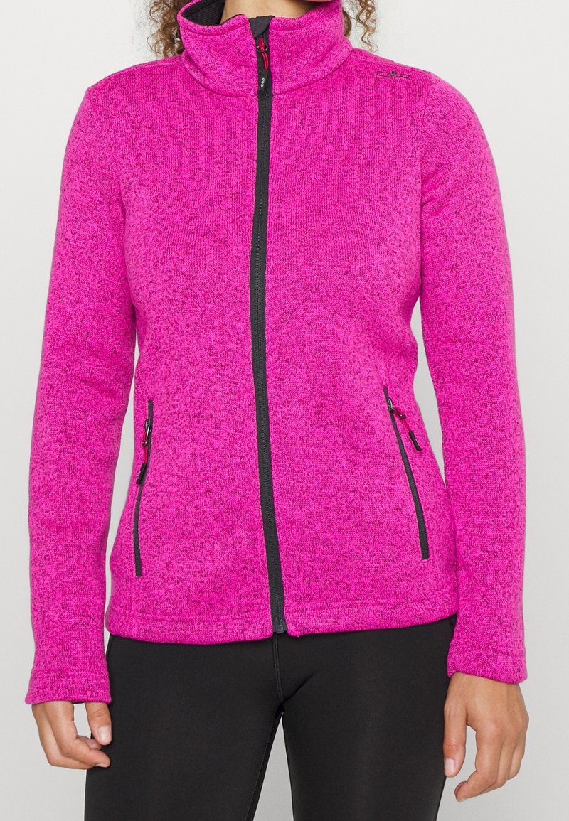 Giacca in pile di un vivace colore rosa con colletto alto, chiusura con zip e dettagli neri. Presenta due tasche laterali con zip e una superficie testurizzata.