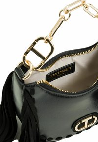 Borsa in pelle lucida nera con manico a catena dorata, chiusura con zip e fodera interna. Dettagli notevoli includono nappine e un accento con logo.