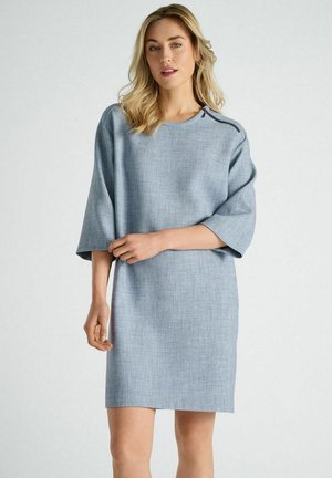 Robe bleu clair à manches courtes en tissu texturé ; elle présente une coupe décontractée et un détail de couture d'épaule subtil.