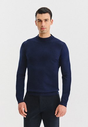 Granatowy sweter z dzianiny z okrągłym dekoltem i długimi rękawami, o gładkiej fakturze i dopasowanym kroju, wykonany z miękkiego materiału.