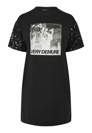 Camiseta negra de manga corta con detalles de lentejuelas negras. El gráfico frontal muestra el texto "MUY DISCRETA" en letras blancas en negrita.