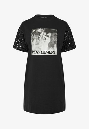 Zwarte t-shirt met korte mouwen, versierd met zwarte pailletten. De voorkant toont de tekst "VERY DEMURE" in vetgedrukte witletters.