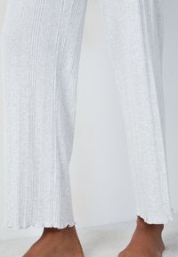 Lichtgrijze ribstof broek met een flared zoom, met een gestructureerd oppervlak en ruwe randdetails bij de enkels.