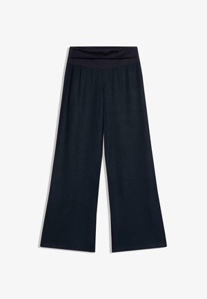 Črne široke hlače z visokim, zloženim pasom, položene na ravno belo podlago.