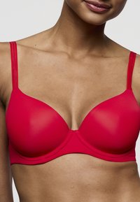 Rode beha met gevormde cups, dunne verstelbare bandjes en een naadloos ontwerp. Glad oppervlak met een lichte glans en een centrale naaddetail.