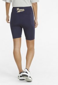 Navyblå högmidjade cykelshorts med elastisk midja och vit "Puma"-logotyp. Slät, elastisk tyg med längd till mitten av låret.