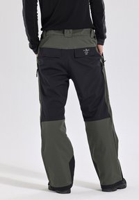 Waterdichte outdoor broek met een zwart-olijfkleurig ontwerp, cargozakken en een verstelbare tailleband. Duurzaam materiaal met verstevigde naden.