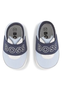 Chaussures pour bébés en tissu bleu et bleu clair avec une semelle blanche, dotées d'un bandeau élastique marine avec le texte "BOSS" en blanc. Taille 17 indiquée.