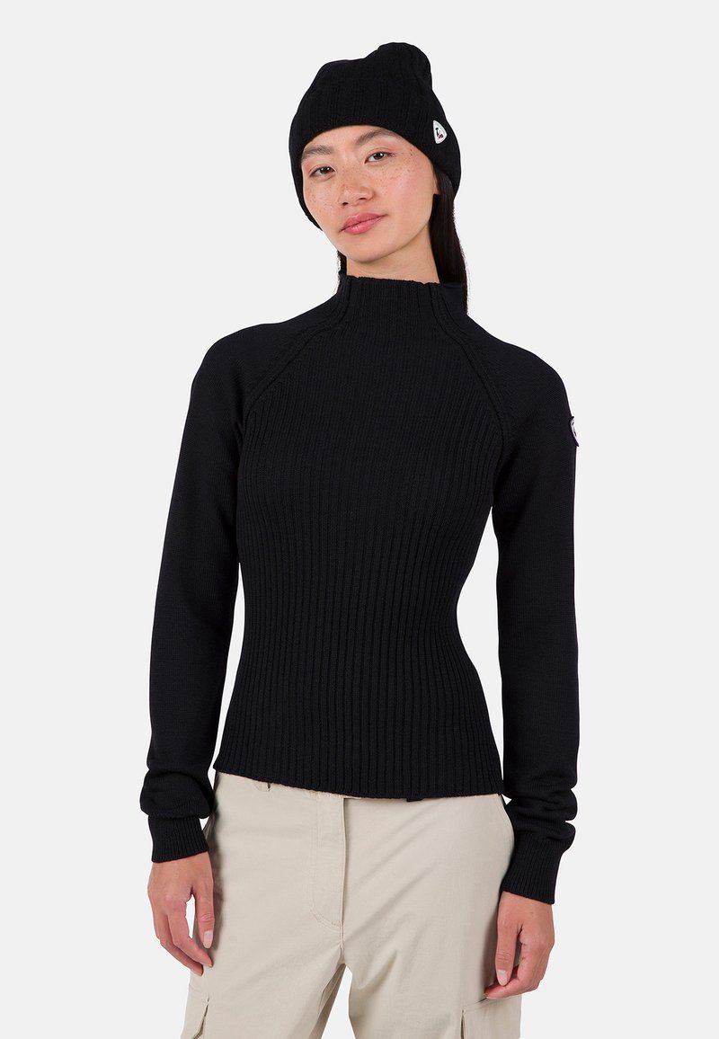 Schwarzer gerippter Pullover mit hohem Kragen und langen Ärmeln, kombiniert mit einer passenden Mütze. Besitzt ein figurnahes Design und strukturierten Stoff.