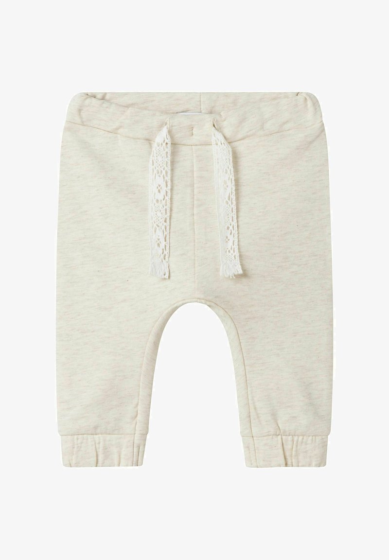 Jasno beżowe dziecięce spodnie dresowe z bawełny z talią na sznurki i ściągaczami. Ozdobione koronkowym detalem na sznurku. Brak kieszeni.