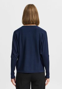 Pull en maille bleu marine, à manches longues et coupe décontractée. Texture lisse, encolure ronde, et bords côtelés aux manches et à l'ourlet. Vue arrière affichée.