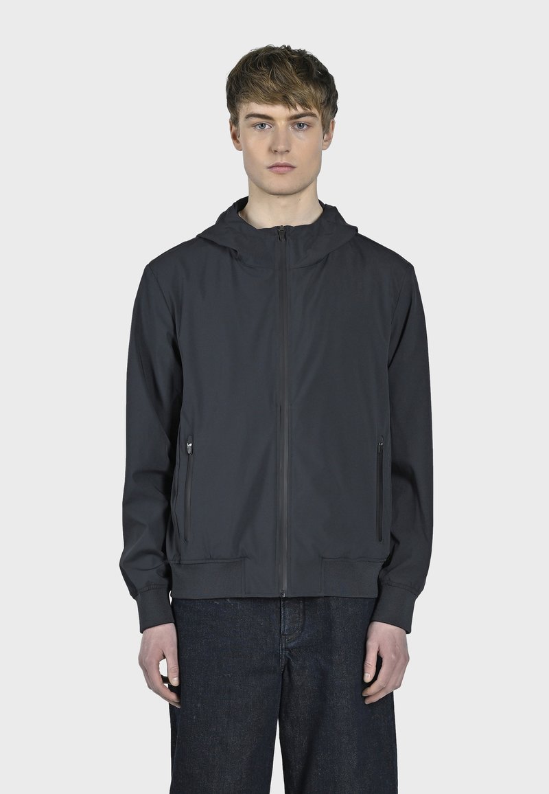 Chaqueta con cremallera de color gris oscuro y capucha, que cuenta con dos bolsillos laterales y puños acanalados. Tejido suave y ligero con un diseño minimalista.