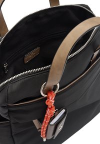 Czarna torba z materiału z brązowymi skórzanymi uchwytami, zamknięciem na zamek, wewnętrzną kieszenią oraz pomarańczowym akcentem w postaci sznurka z małym dołączonym portmonetką.