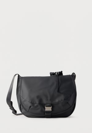 Czarna wodoodporna torba na ramię z klapką, metalową klamrą, regulowanym paskiem na ramię i wewnętrzną sakiewką ze ściągaczem.