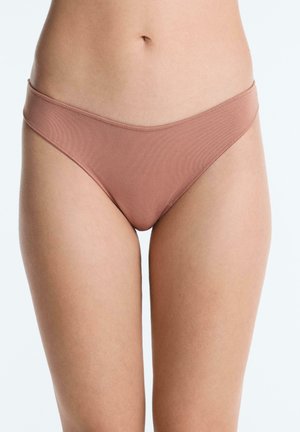 Ženska nosi rebrasto svetlo rjavo perilo v stilu bikinija, prirezano na sredini trupa in zgornjem delu stegen, na enobarvni svetli podlagi.