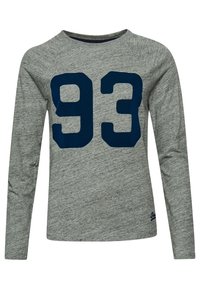 Pitkähihaisen harmaan t-paidan tekstuuri on mielenkiintoinen, ja sen etuosassa on suuri laivastonsininen "93" -painatus sekä pyöreä kaula-aukko.