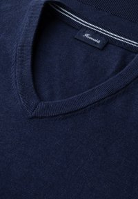 Granatowy sweter z dekoltem w szpic, z prążkowanym kołnierzem i paskowanym detalem na wewnętrznej stronie szyi, z widoczną wszytą metką materiałową.