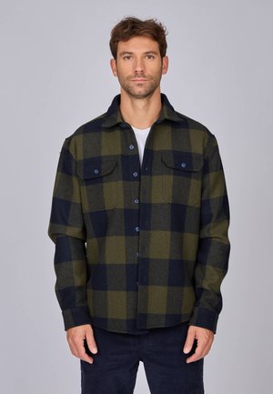 Chemise en flanelle à motifs tartan en vert foncé et bleu marine. Design à boutons avec deux poches sur la poitrine. Tissu doux et texturé avec une coupe décontractée.