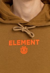 Brown hoodie featuring a drawstring with a textured finish. Bold "ELEMENT" logo in orange, with a circular graphic below.