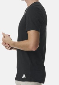 Svart bomulls t-shirt med korta ärmar, rundad halsringning, figursydd design, med en vit Adidas-logotyp nära nederkanten till vänster.