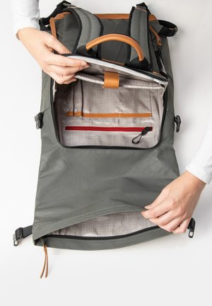 Grau farbene Rucksack mit einer glatten, matten Oberfläche. Innen gibt es ein gemustertes Futter, Lederakzente und mehrere Organisationsfächer.