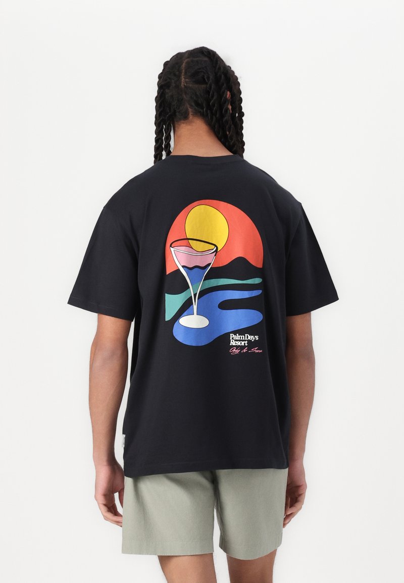 Sort bomulds T-shirt med et farverigt grafisk print af en solnedgang, bjerge og et cocktailglas på bagsiden. Korte ærmer, afslappet pasform.