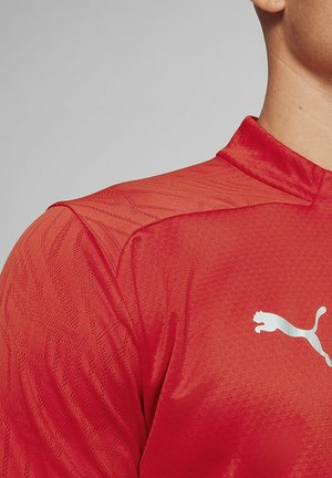 Rotes Sportshirt mit strukturiertem Design, hohem Kragen und silbernem Puma-Logo auf der Brust. Aus atmungsaktivem Stoff hergestellt.