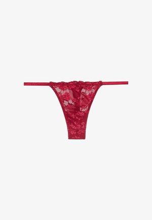 Tanga rojo de encaje con bordado floral, material transparente y tirantes elásticos finos, diseñado con un corte de tiro bajo y cobertura mínima en la parte trasera.