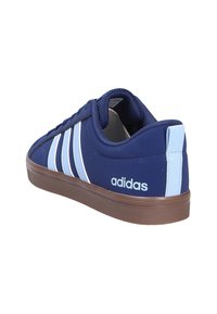 Tummansiniset lenkkarit valkoisilla raidoilla, kumipohja, nyörityssuunnittelu ja Adidas-logot sivulla ja kantapäässä. Sileä materiaali, jossa on teksturoitu pohja.