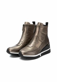 Botines metálicos bronce con una textura suave y acolchada, que cuentan con un cierre de cremallera, acentos en negro y detalle de suela blanca.
