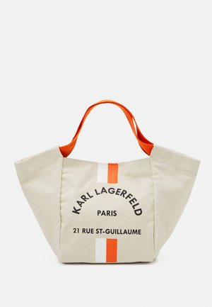 Bolsa de tela beige con asas naranjas, que presenta una franja vertical blanca y naranja. El texto incluye "Karl Lagerfeld Paris" y detalles de dirección.