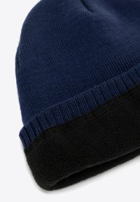 Granatowa dzianinowa czapka z mankietem z czarnego polaru. Charakteryzuje się miękką teksturą i prążkowanym wzorem zapewniającym ciepło i komfort.