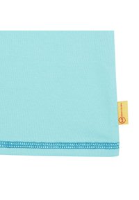 Tela de algodón de un azul claro con una superficie suave, que presenta un dobladillo en azul contrastante y una pequeña etiqueta amarilla con un logo rojo en el borde.