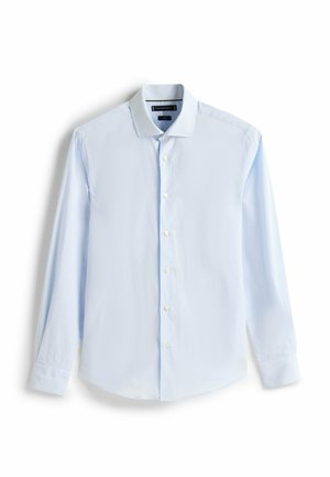 Lyseblå skjorte med lange ærmer lavet af bomuld. Har en klassisk krave, knaplukning foran og rundet kant. Ingen mønstre eller pynt.