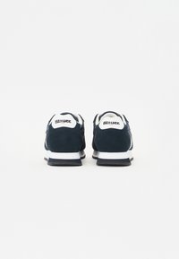 Zapatillas de ante azul marino con detalles blancos, talón acolchado y logo en la parte trasera. Presentan una suela texturizada para mayor tracción y soporte.