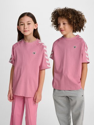 To børn iført matchende lyserøde skjorter med hvide Chevron-striber på ærmerne; den ene i lyserøde bukser, den anden i grå joggingbukser.