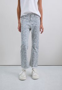 Jeans din denim de culoare albastru deschis cu un model de leopard în nuanțe de navy și corai, având o croială dreaptă și margine desfăcută. Asortate cu adidași albi.