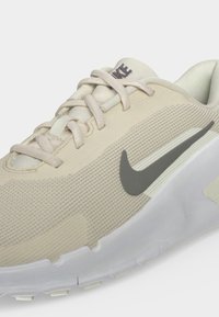 Ανοιχτό μπεζ αθλητικό παπούτσι Nike με λευκή σόλα, γκρι λογότυπο Nike στο πλάι και αντίστοιχα μπεζ κορδόνια σε υφασμένο επάνω υλικό.