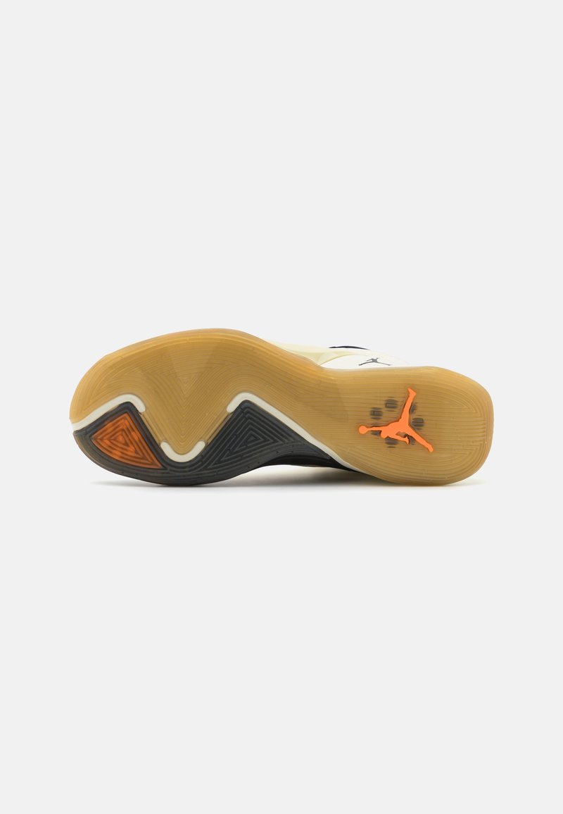 La suela de la zapatilla de baloncesto presenta una base de goma natural con un patrón en zigzag, acentos en negro y un logo naranja. Texturizada para proporcionar agarre y durabilidad.