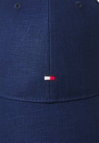 Cappellino blu navy realizzato in tessuto testurizzato. Presenta un piccolo logo ricamato in rosso, bianco e nero sul davanti. Visiera arrotondata.