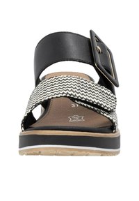 Schwarze Ledersandale mit gewebtem weißen und schwarzen Riemen, breitem Schnallen-Detail, flacher Sohle mit strukturierter Oberfläche und natürlicher brauner Fußbett.